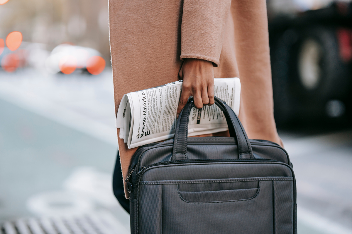 Crop businesswoman with newspaper crossing road