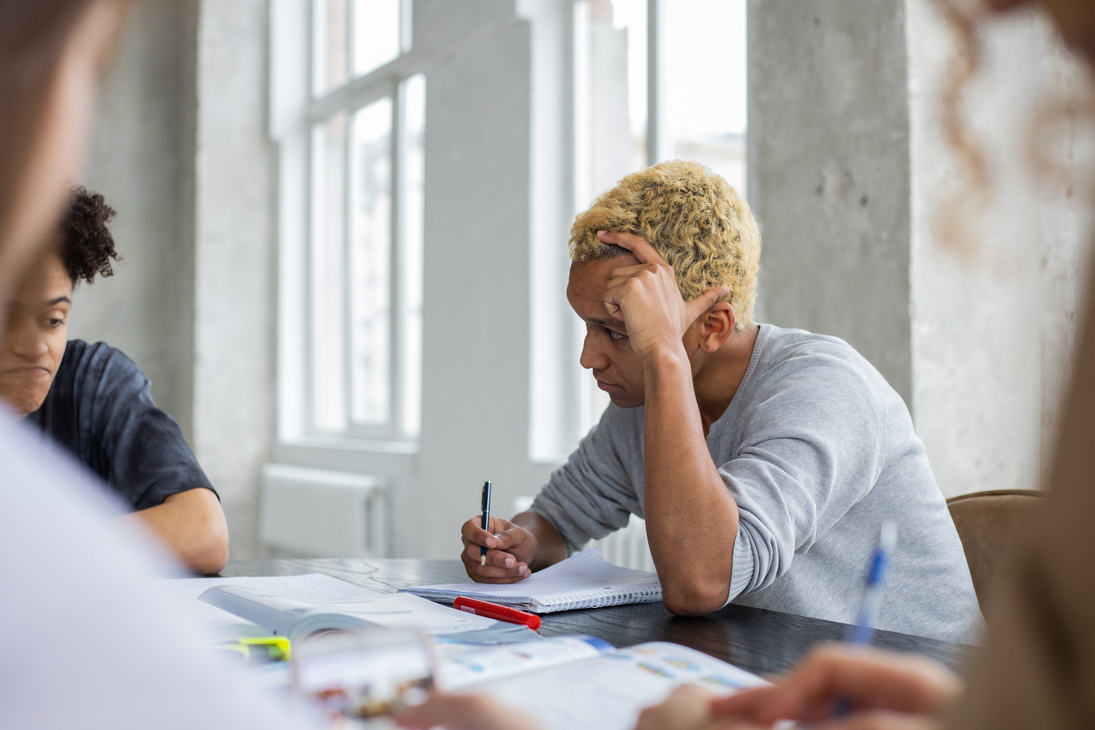 Serious black man studying with anonymous classmates