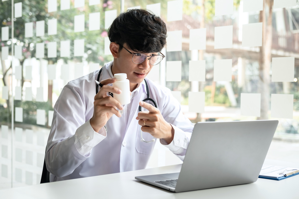 A Male Doctor Is Pointing at the Bottle of Pill to Recommend Med