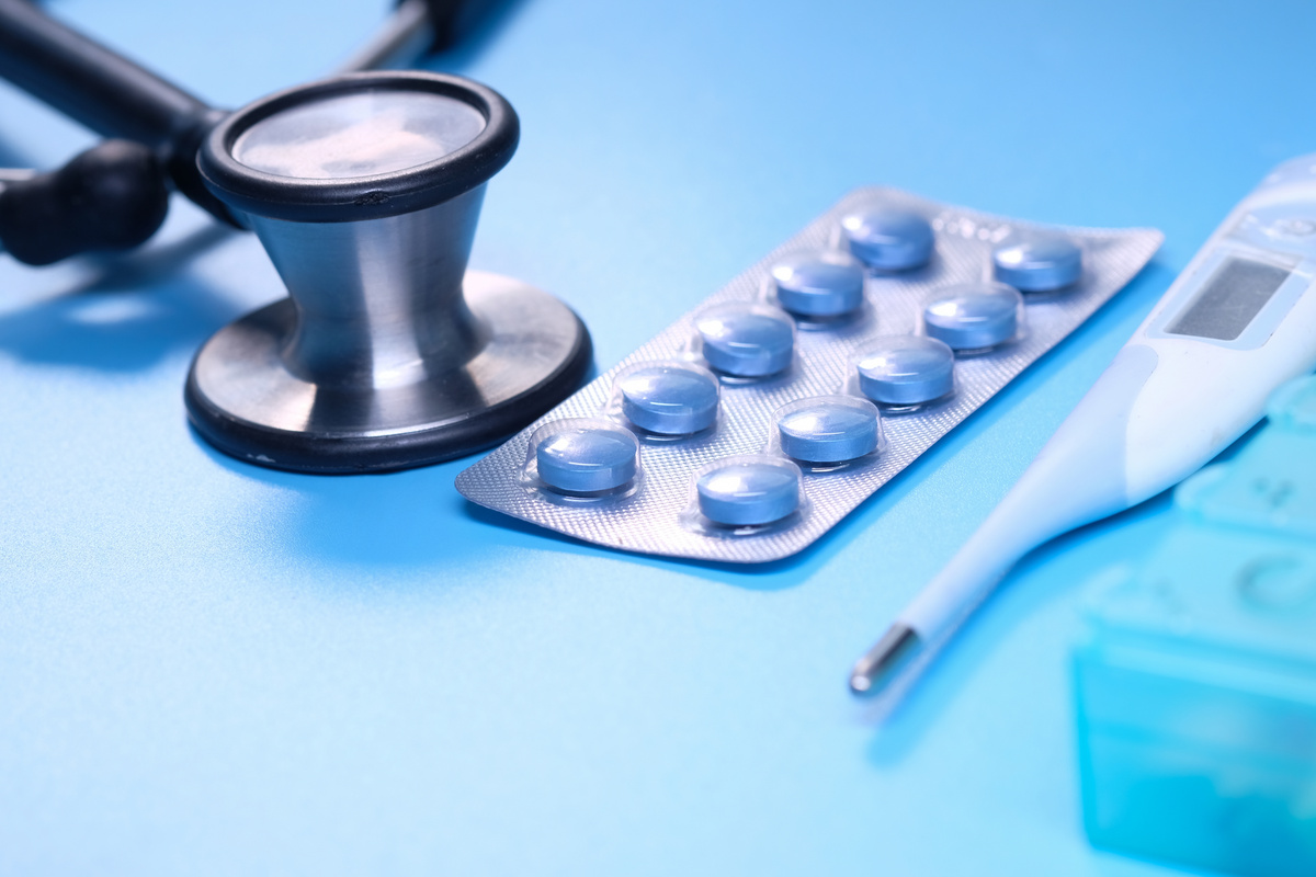 Blister Pack, Thermometer and Stethoscope on Blue Background